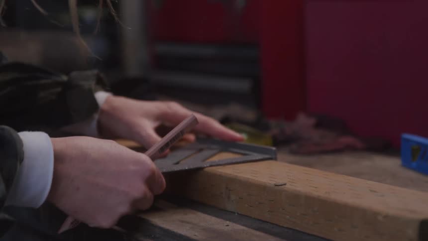Pair of hands of a person making drawings with a ruler on a piece of wood