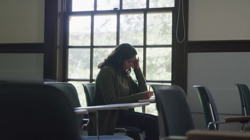 Woman sitting at a desk in a classroom writing