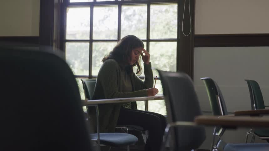Woman sitting at a desk in a classroom writing