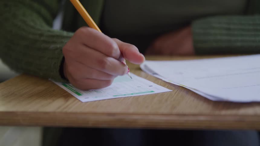 Person with a pencil filling out a template on a table