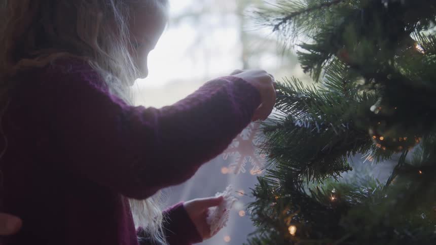 Little girl putting decorations on a christmas tree