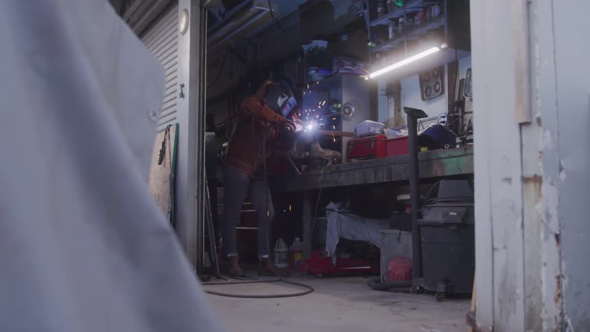 Person with protective mask welding an object and sparks emitting around