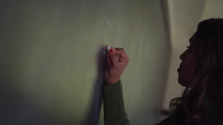 Woman in white jeans writing on a blackboard