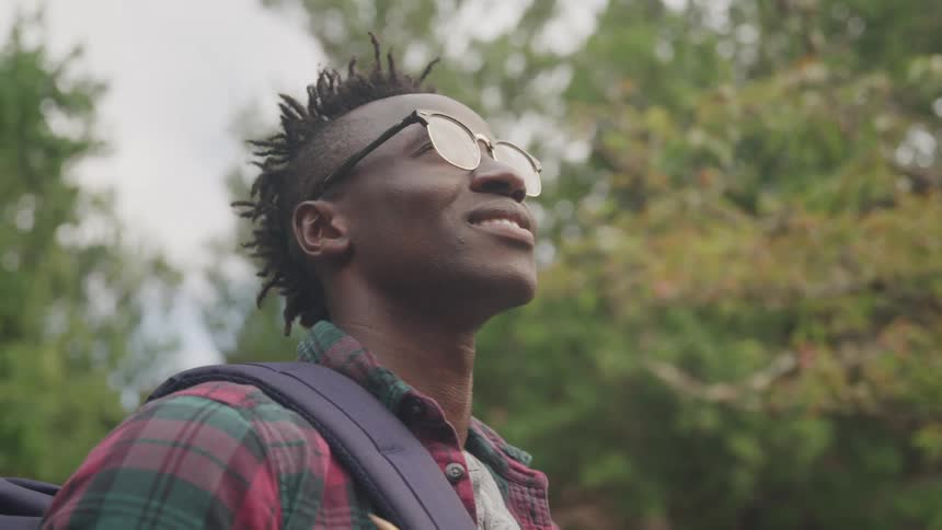 Man wearing glasses outdoors in an environment surrounded by trees