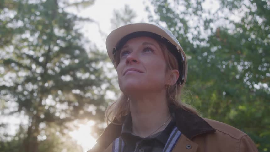 Woman wearing a white helmet in an outdoor setting surrounded by trees