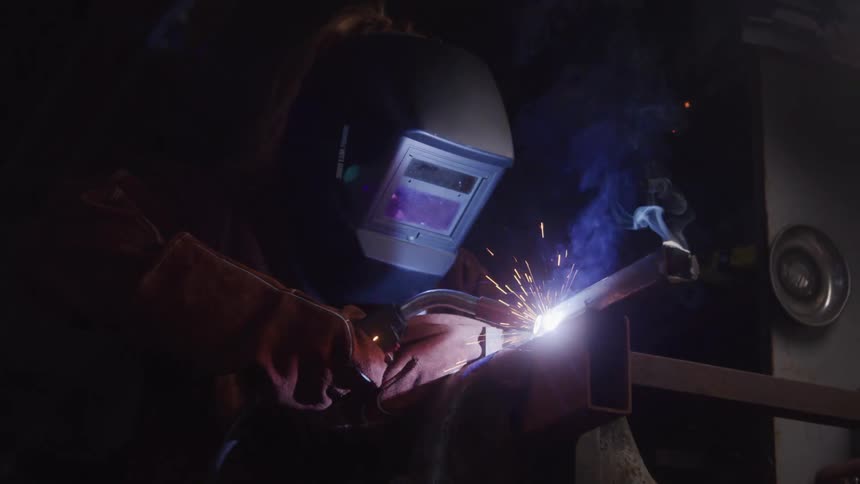 The welder is using a torch on the metal