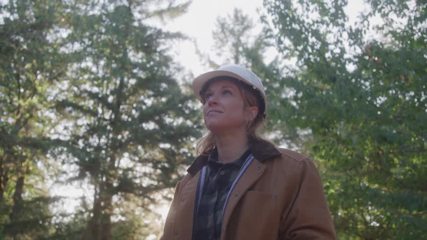 Woman wearing a white helmet outdoors in an environment surrounded by trees