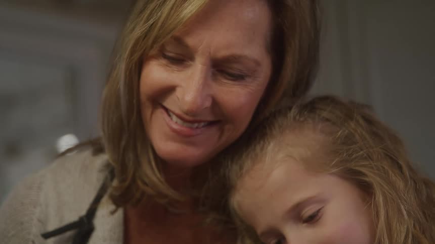 The video shows an adult woman likely a mother smiling down at a young girl with blonde curly hair indicating a warm and affectionate interaction between them