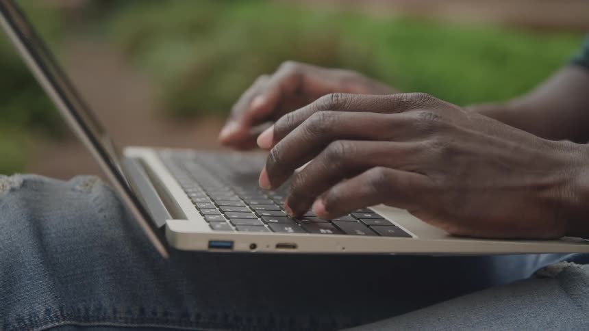The man is typing on the keyboard of his laptop
