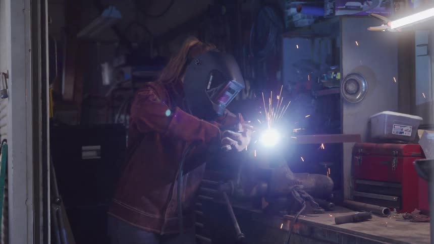 The woman is torching metal in a clamp