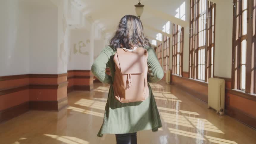 Woman with a backpack walking in a university hallway