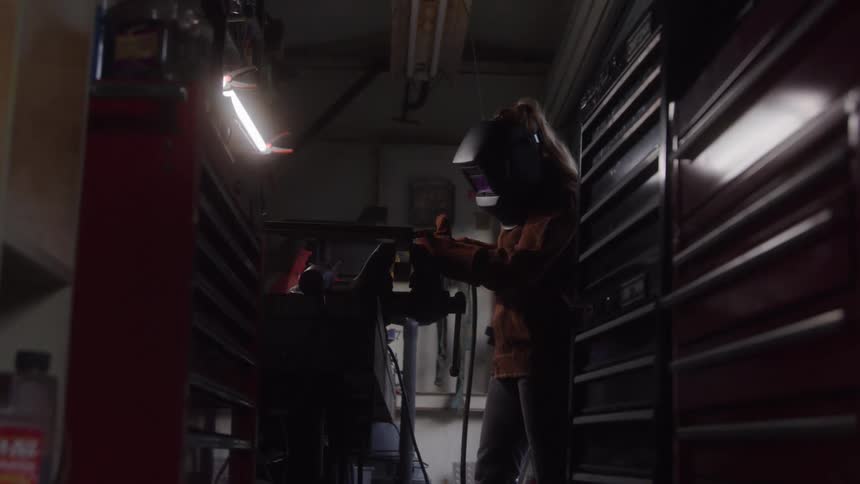 Woman in protective helmet welding an object