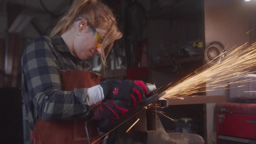 Woman with protective glasses handling a chainsaw on a metal