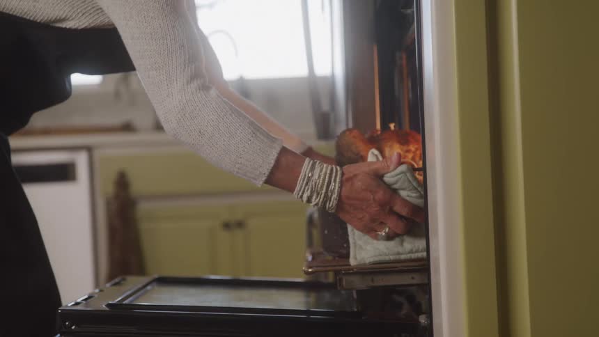 The video shows a persons hands wiping down the exterior of a kitchen appliance possibly an oven or dishwasher with a cloth the movements are precise and focused on cleaning the surface