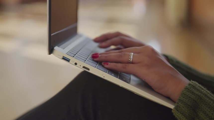 Pair of womans hands typing on a laptop