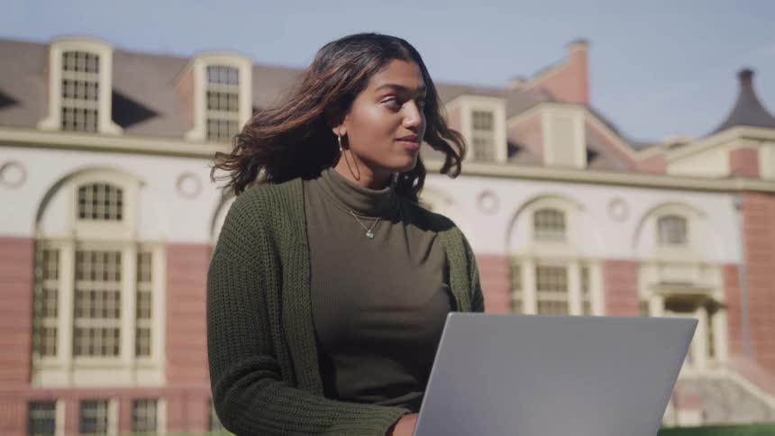 Woman sitting typing on laptop outdoors