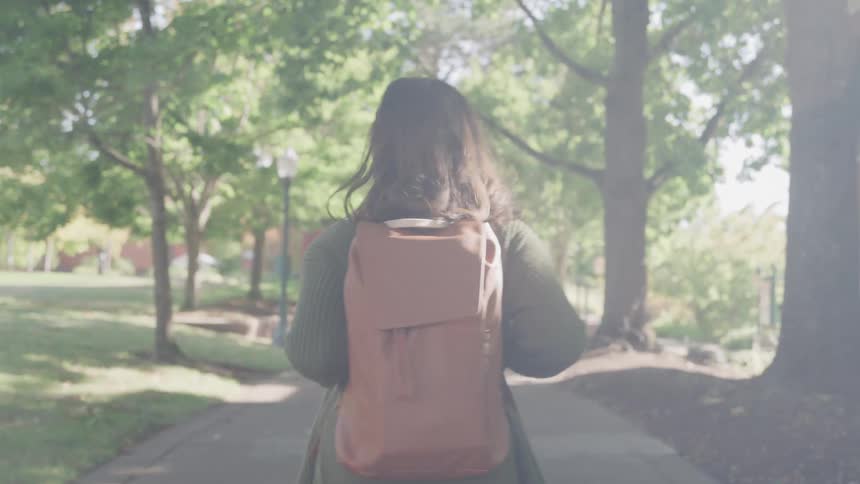 The woman is walking on campus