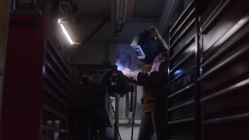 A woman is welding in the workshop