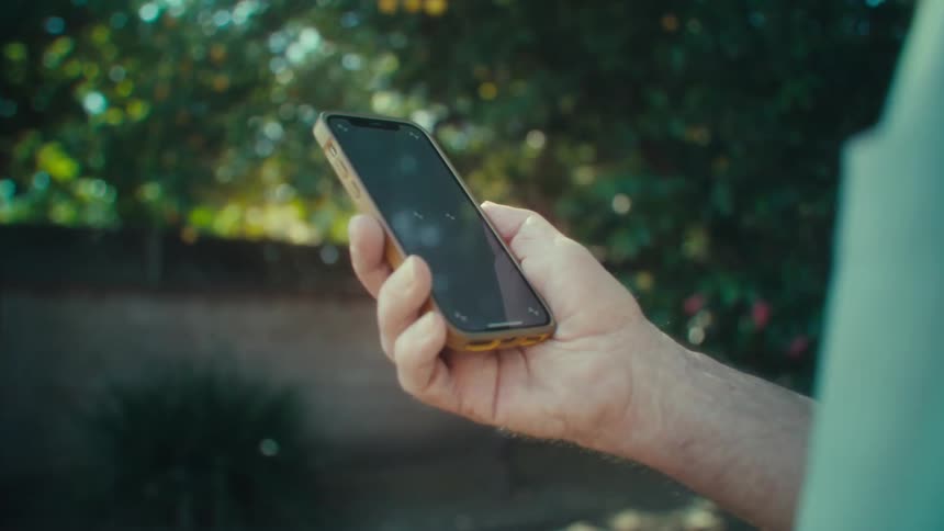 A man in his yard is holding his cell phone