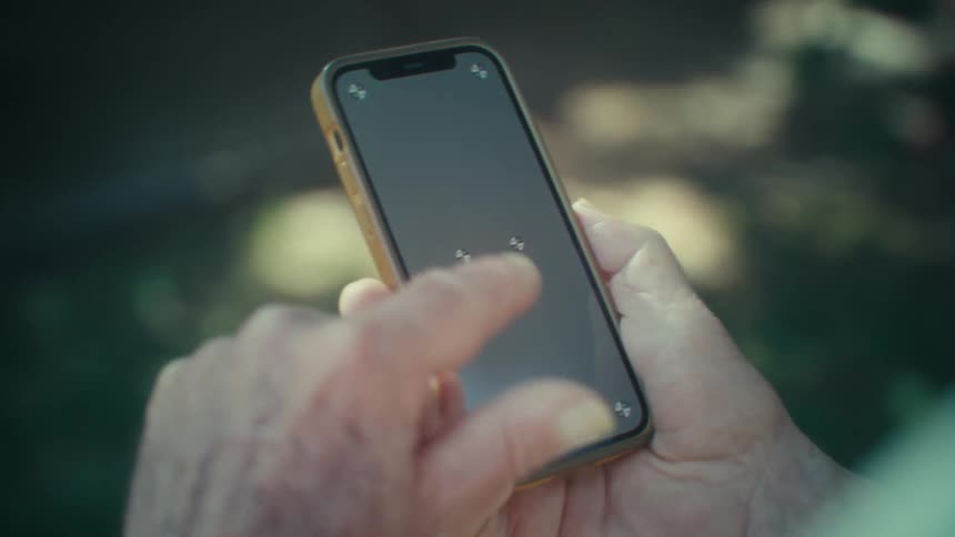 Pair of hands of an elderly person interacting with a smartphone