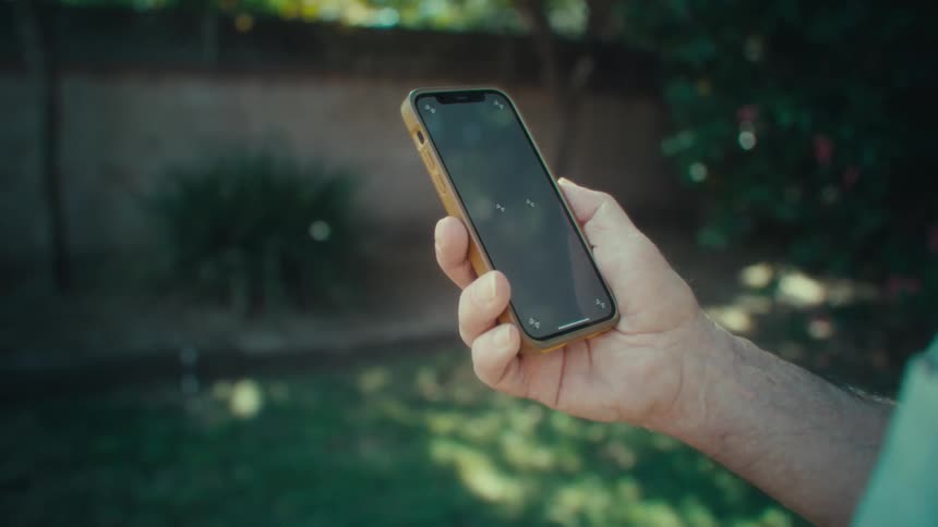 Person in a backyard holding a smartphone