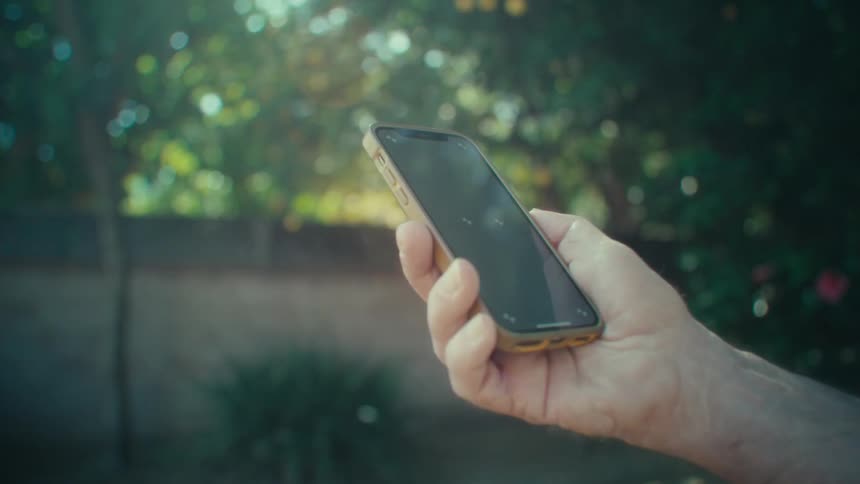 Man holding a mobile phone in a garden