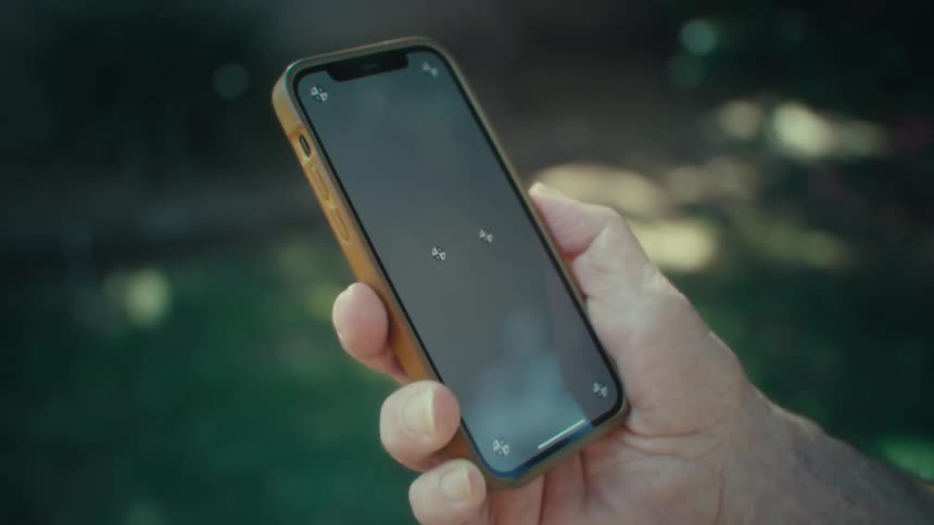 The video shows a closeup of a persons hand holding a smartphone with a blank dark screen the phone case appears to be a light brown or tan color