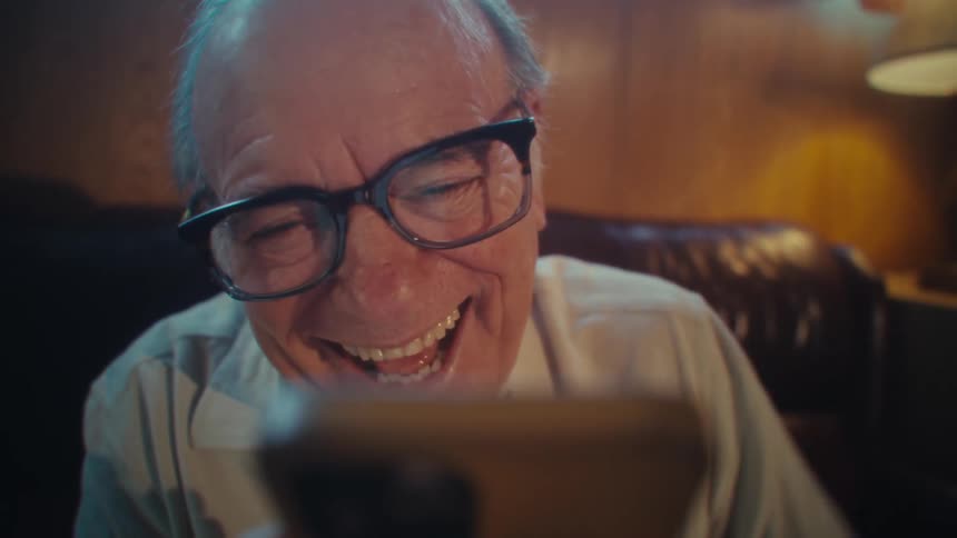 Closeup eyelevel shot of an elderly man who appears to be experiencing a moment of intense excitement looking to his smartphone