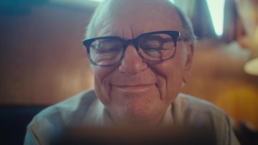 The man stops to laugh while looking at his cell phone