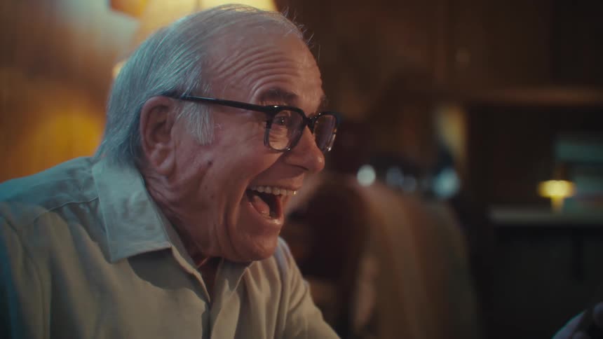 A man laughs while looking at his phone at home