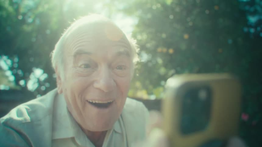Man jumping and cheering while looking at a phone in his yard