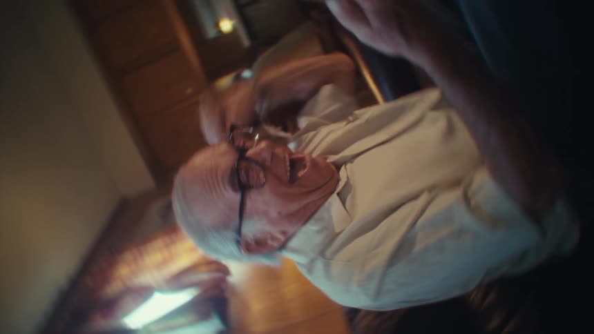 Elderly man smiles joyfully at his smartphone indoors