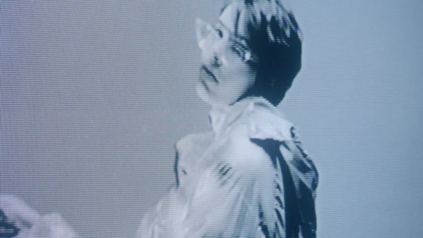 The face of a person looking straight ahead in various poses as seen through an image on an old monitor