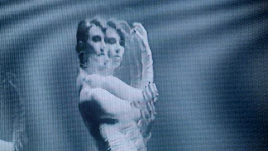 The model is posing wearing a white dress