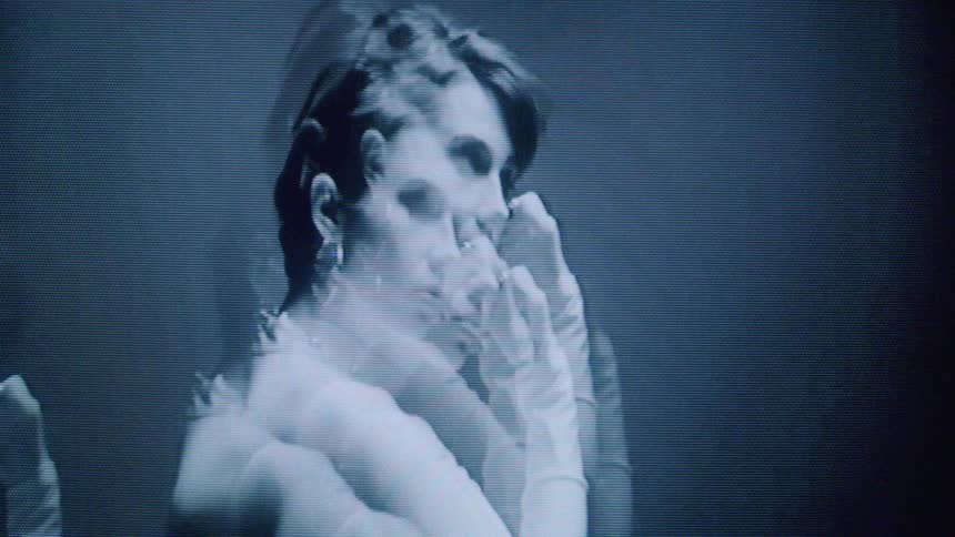 A model is posing in the black and white footage