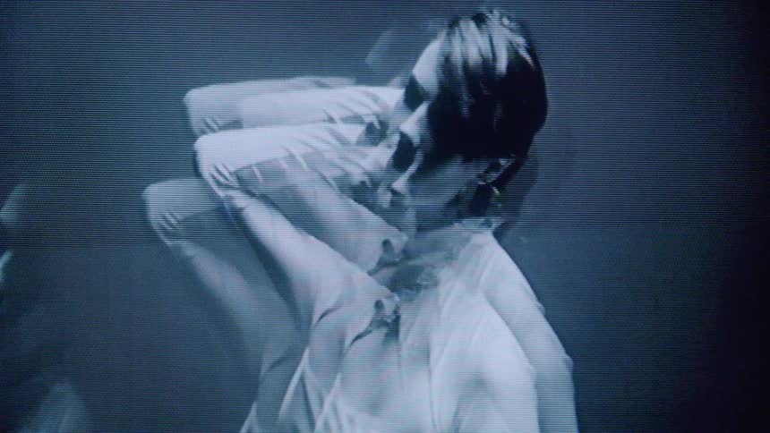 The video displays a glitchy monochromatic black and white closeup of a persons face with pixelation and visual distortion creating a digital or vintage television effect the face is predominantly shown in profile occasionally shifting to face for