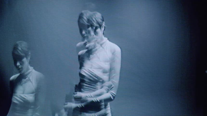 A ghostly image of a woman in a dress appears on a distorted glitchy screen with a vintage dreamlike effect