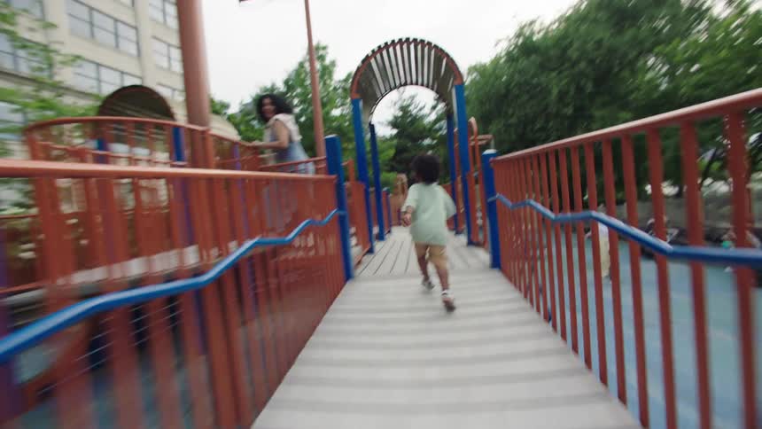Boy runs excitedly through a colorful playground bridge