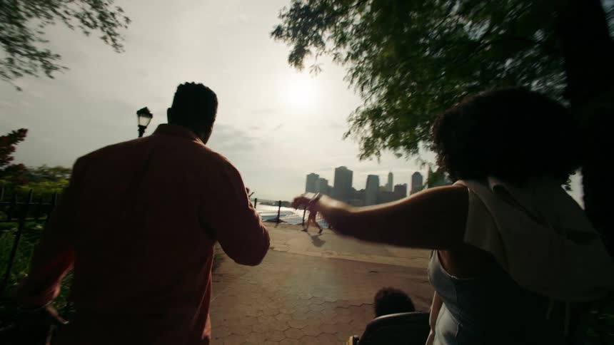 A couple walking toward a shoreline fence with the mother pushing their child in a stroller