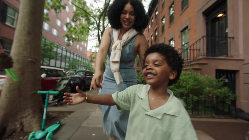 Father blows bubbles as mother and son play on the street