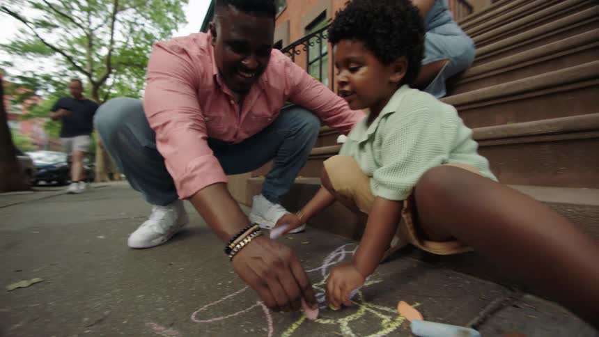 Father and son drawing with chalk on a suburban sidewalk