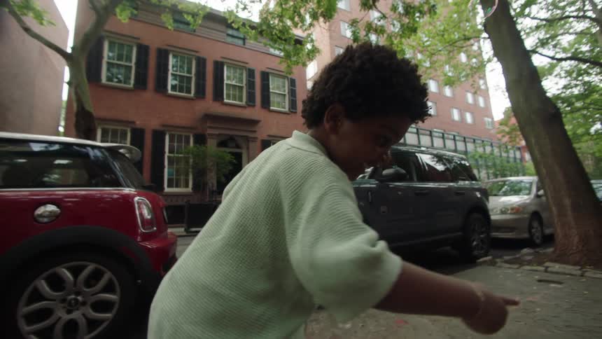 Boy on the urban sidewalk accompanied by his father playing with soap bubbles