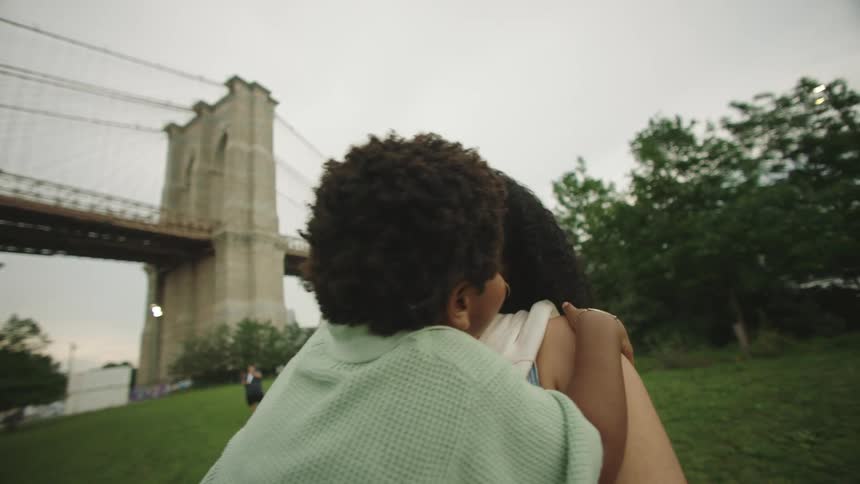 Close up of mother carrying her son playfully while standing outdoors in a park during daytime