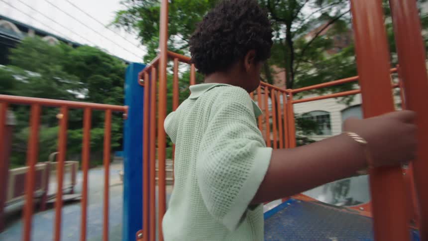 The video shows an adult and a young child playing at a playground with the adult helping the child operate a red circular play equipment both individuals are smiling and appear to be enjoying the activity together
