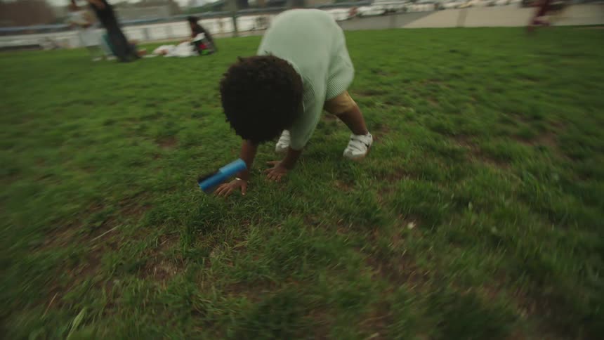 Family plays with a toy rocket launcher in a busy riverside park across from downtown on a summer day