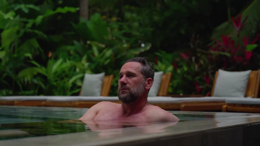 A man relaxing in an outdoor pool at midday