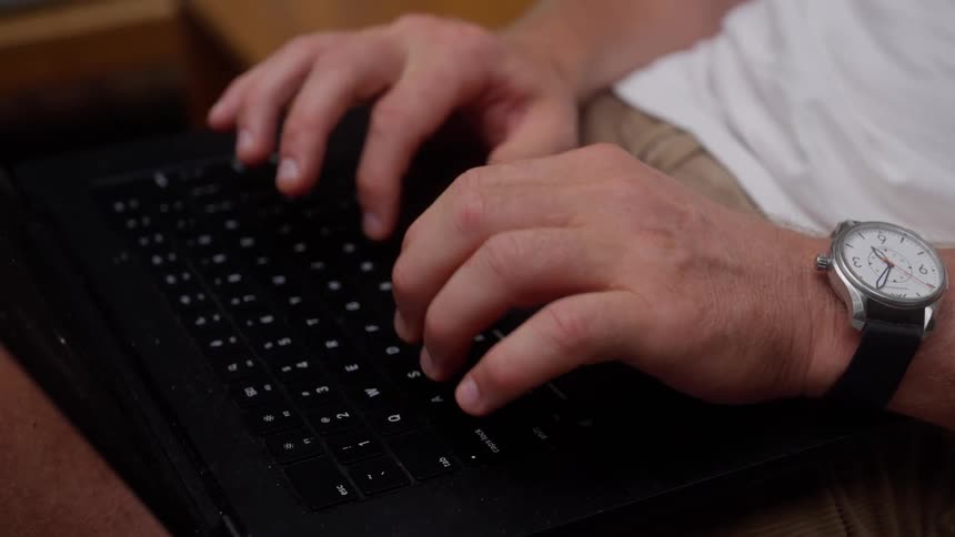 A man types fast on his laptop