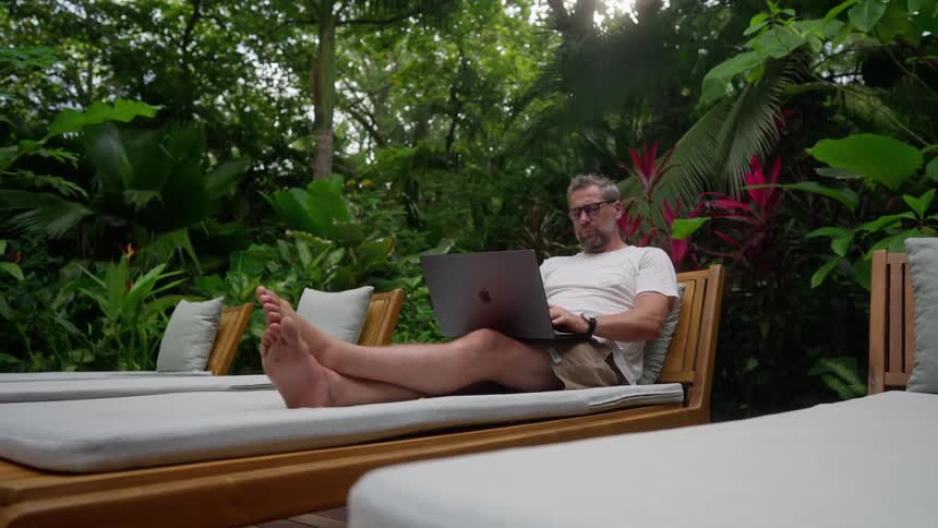 Man works remotely on vacation in tropical garden