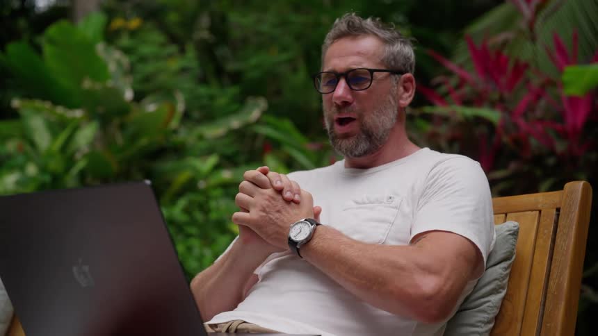 Man sitting with laptop and making expression of relief