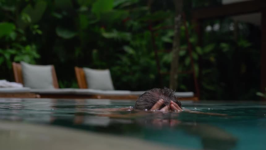 A man lounges peacefully in the pool enjoying a moment of relaxation